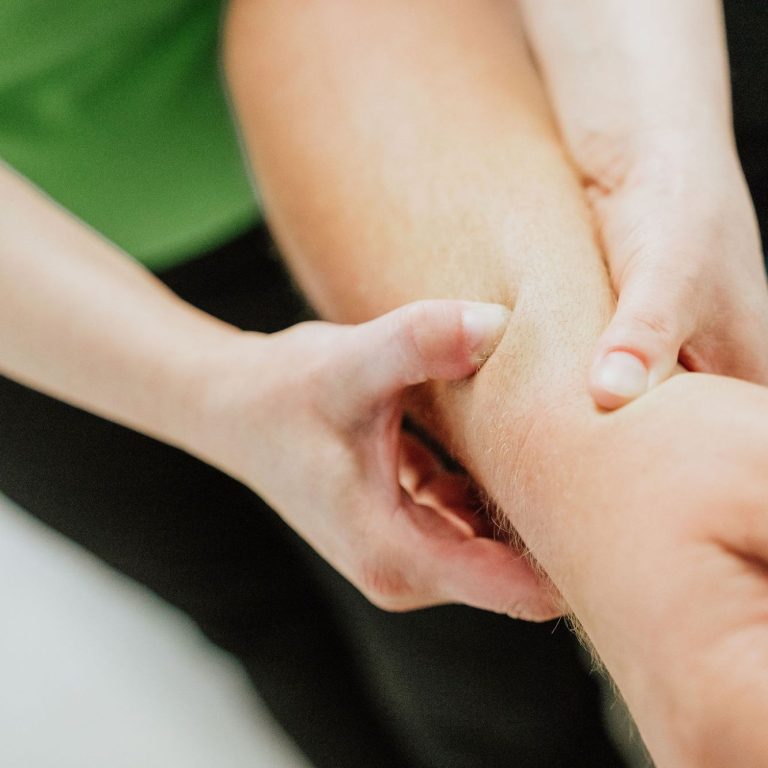 Eine Hand führt eine Massage oder Therapie an einem Unterarm durch.